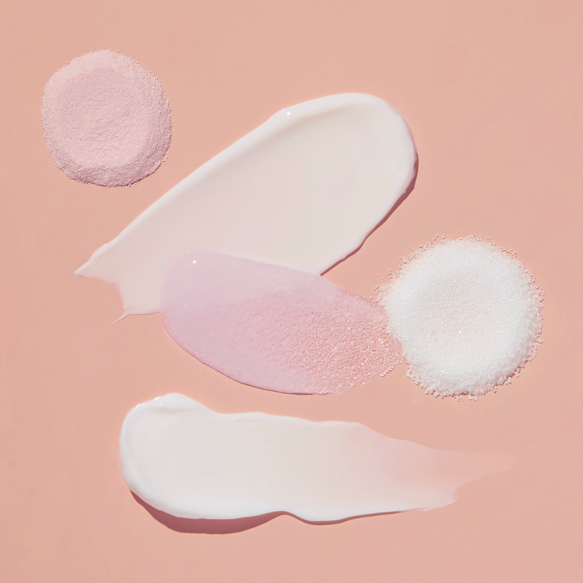 Product texture of Fizz powder, Salt, Scrub Mud masque, Massage butter on light pink background